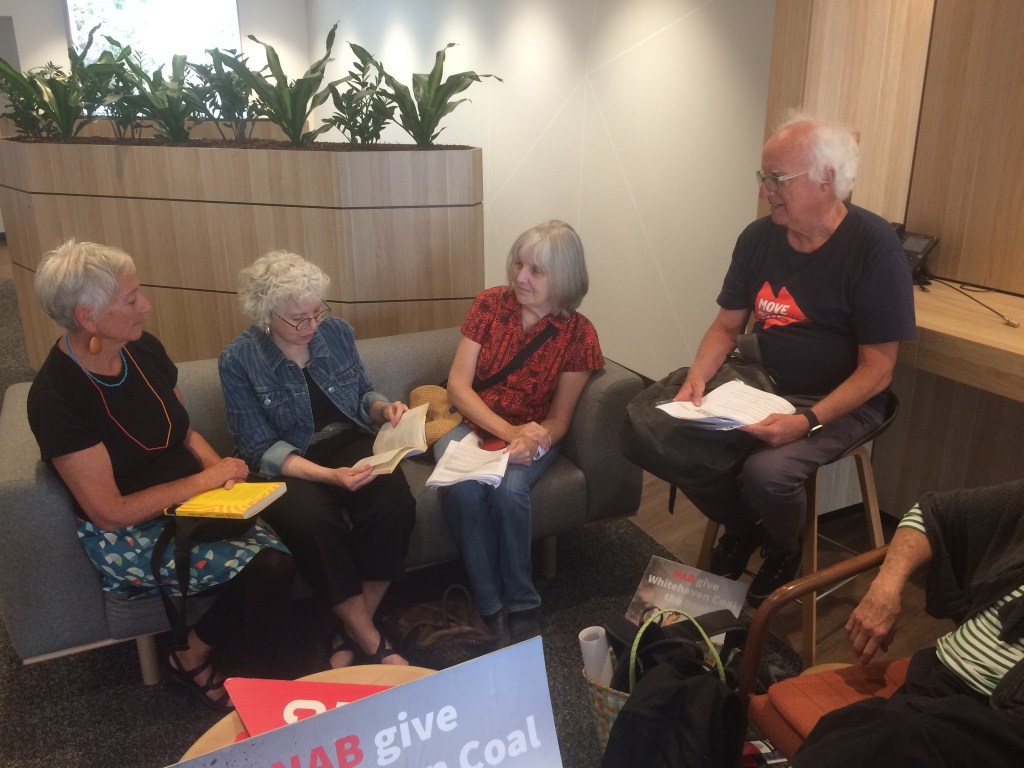 Three women on a couch, a man on a high stool, part of a fourth person in the right foreground. All are listening as the woman in the middle readds
