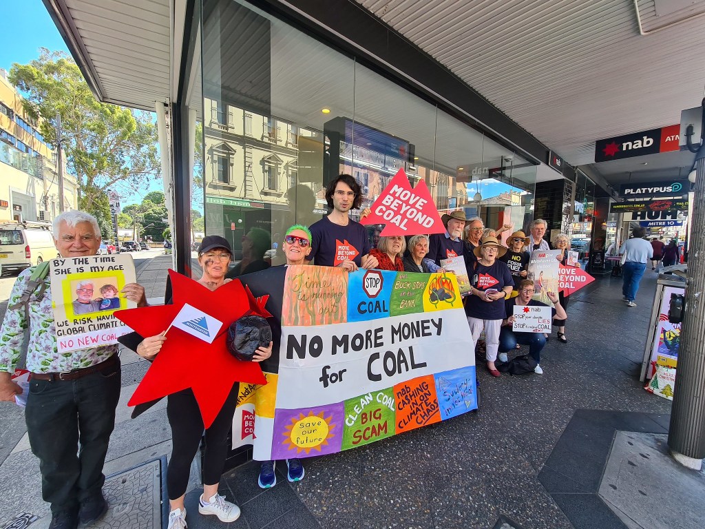 Fourteen people lined up outside the Newtown branch of NAB, with a prominent banner reading 'No More Money for Coal'